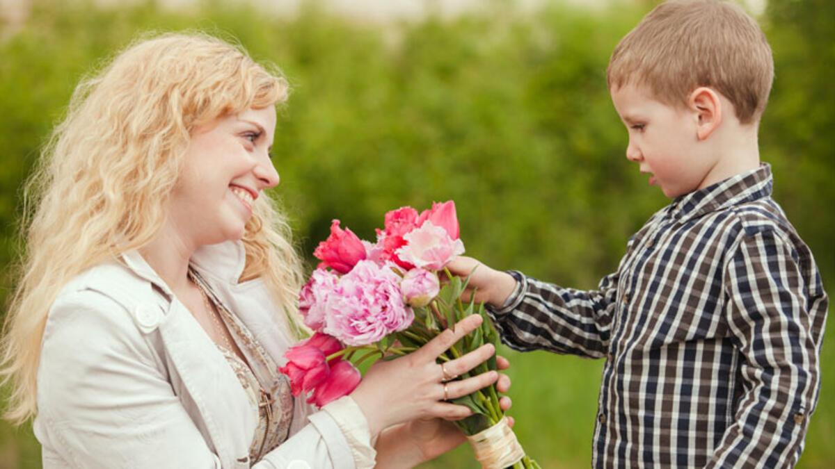 Мальчик дарит цветы маме