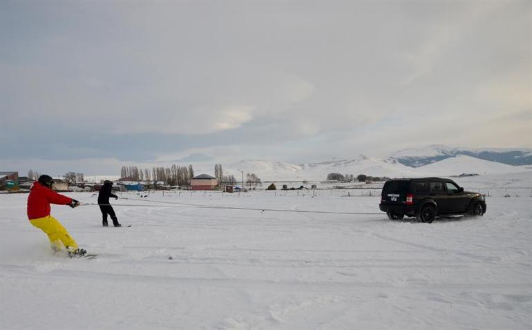 Arazi aracıyla karda snowboard yaptılar