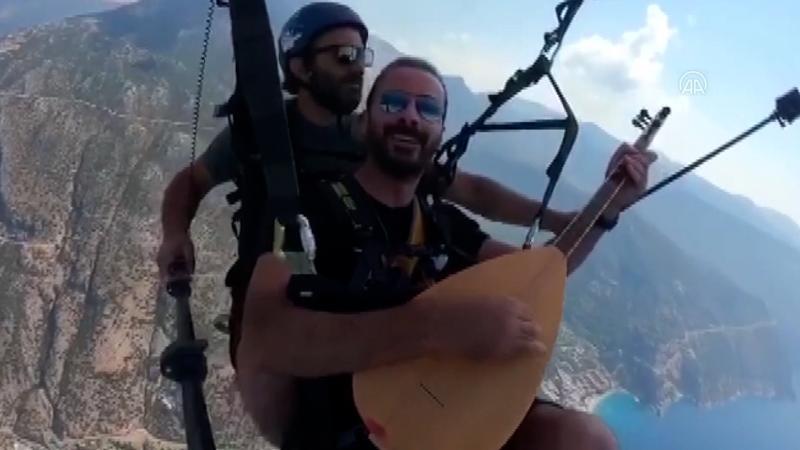 Yamaç paraşütüyle atlayan ses sanatçısı, gökyüzünde saz çalıp türkü söyledi